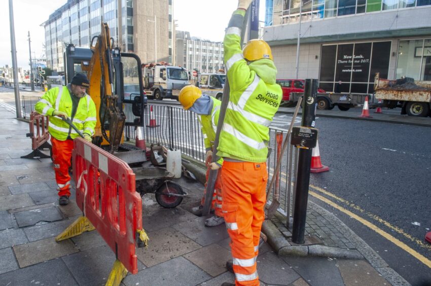 Council workers installing metal poles on Guild Street for LEZ signs
