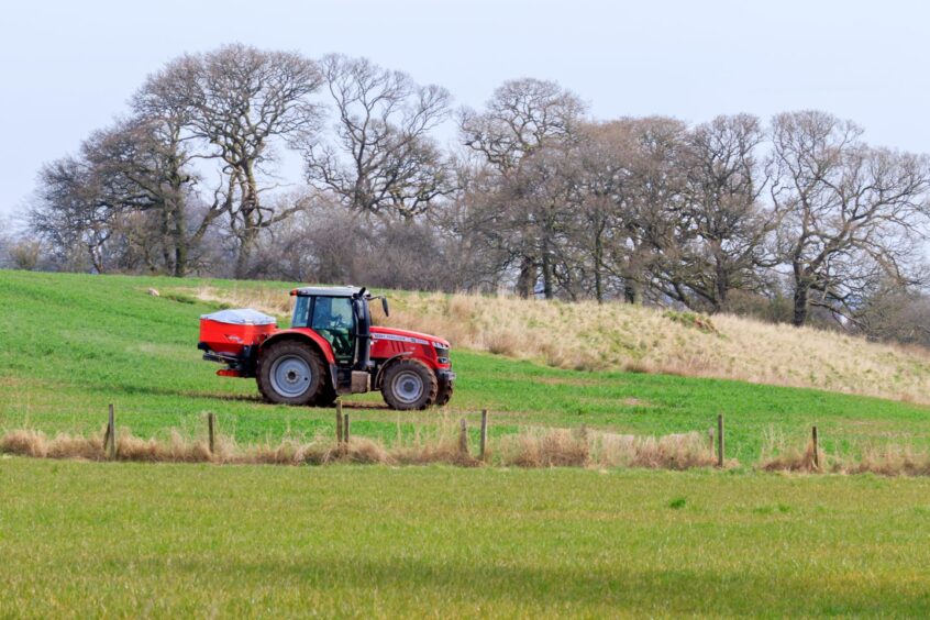 Tractor spreading fertiliser onto farm pasture