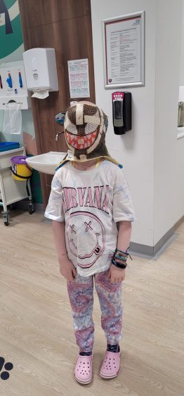Aurora Farren, 8, wearing the radiotherapy mask she painted.