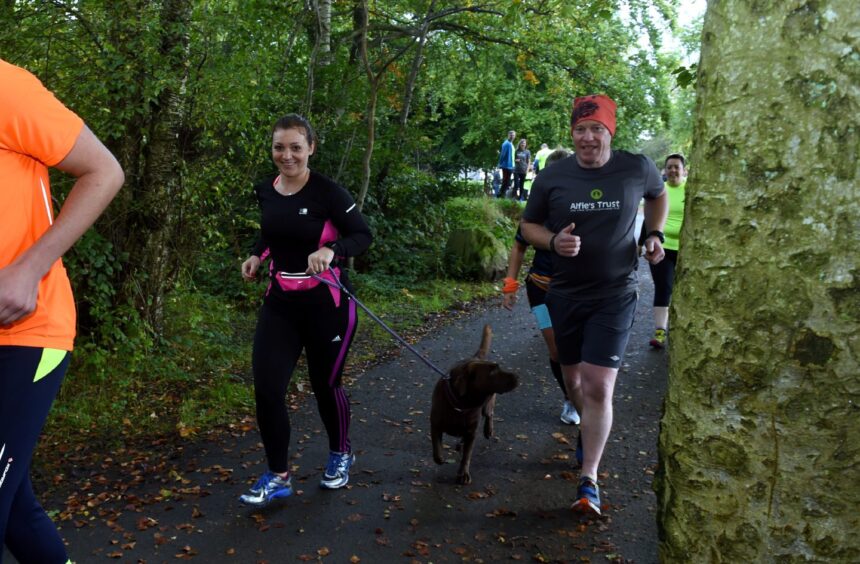 Runners jog with a dog in Hazlehead Park, one of the best places to run in Aberdeen