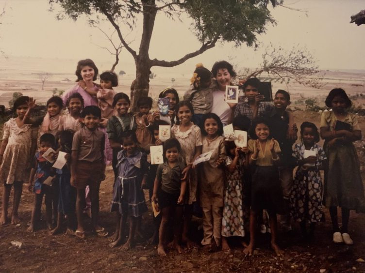 Maggie Macleod stands amid a sea of children in India, where she worked at a mission hospital