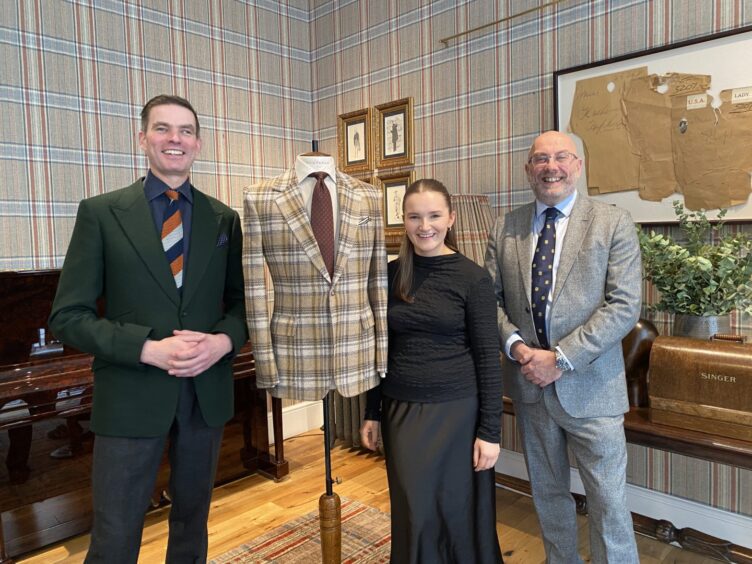 Lois poses with her jacket next to Campbell Carey, head cutter at Huntsman and Iain Milligan, managing director of Huddersfield Fine Worsteds. 
