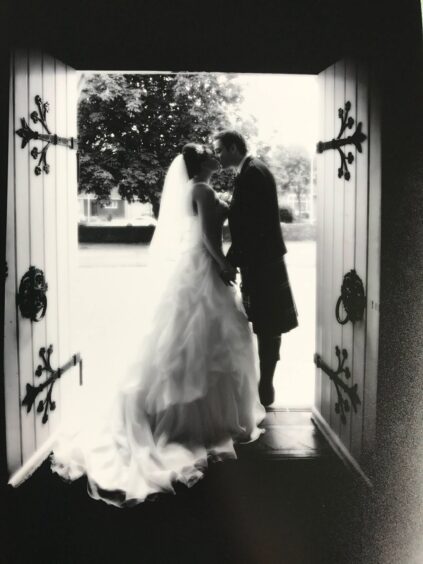 Jenna and Iain McGettrick pictured in the doorway of a church, kissing, on their wedding day.