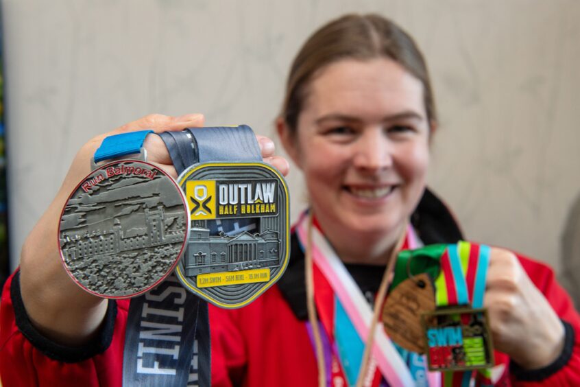 Tamsin Law, from Aberdeen, holding medals she won competing in triathlon competitions.
