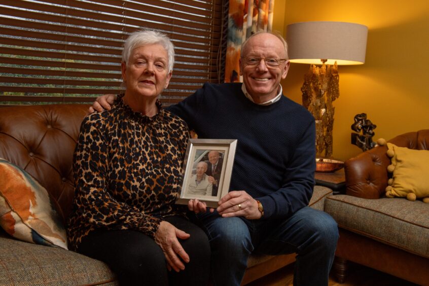 Bridge of Don couple who fundraised for dementia sitting with a photo of their fathers