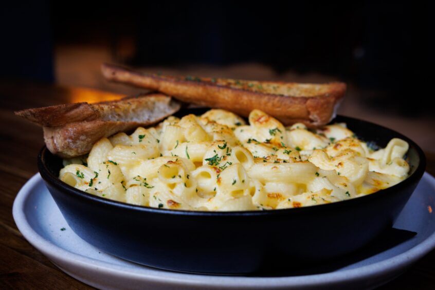 A photo of some delicious-looking mac and cheese with garlic bread.
