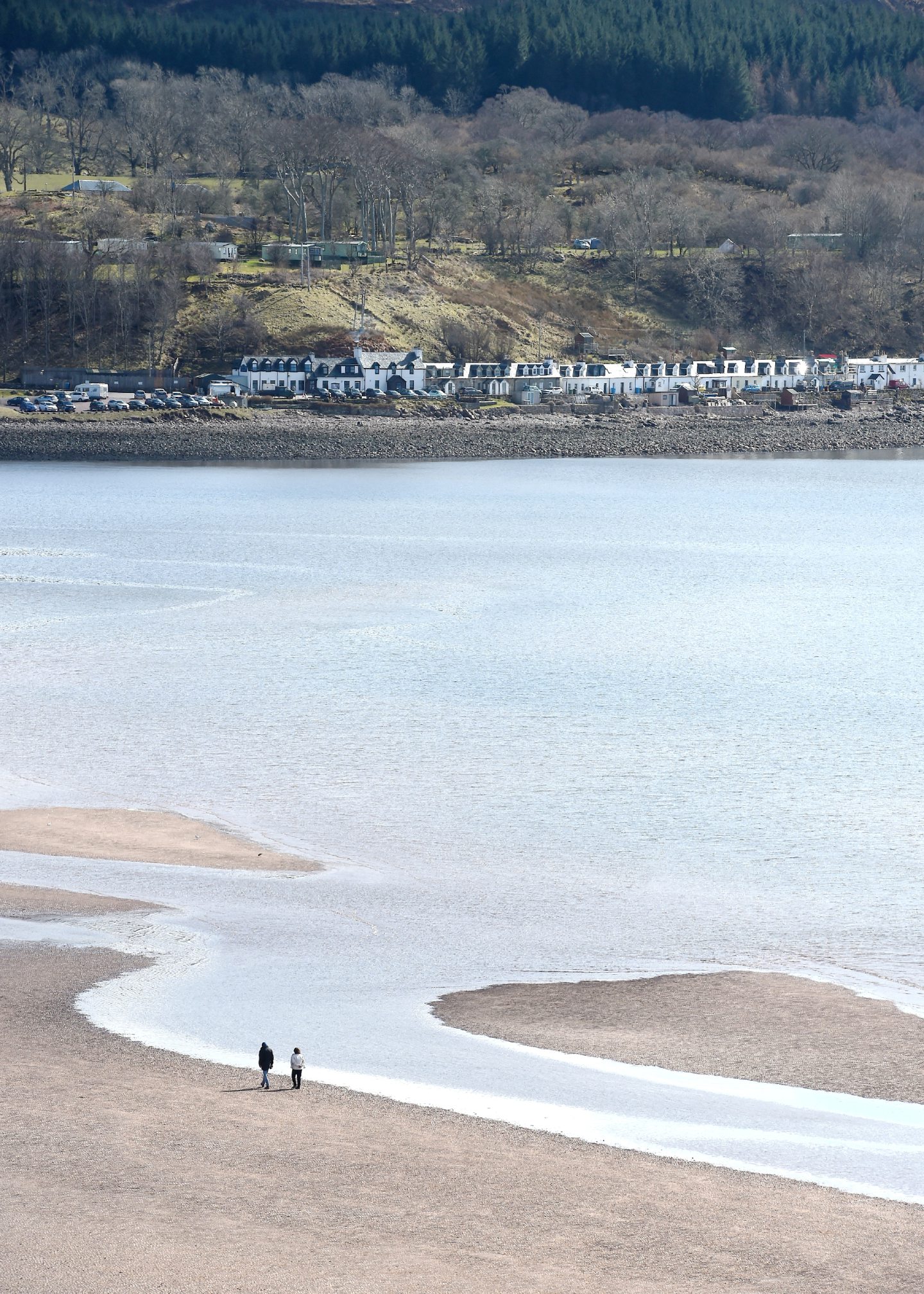 Walkers on the sand of Applecross Bay with the village beyond.