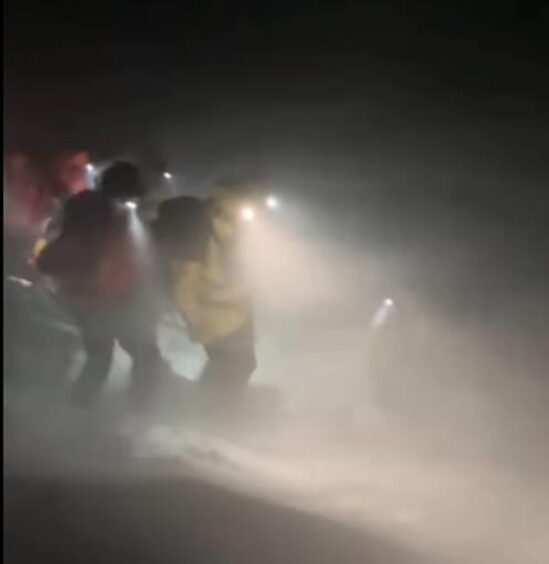 Mountaineers walking through a snow blizzard in the Cairngorms.