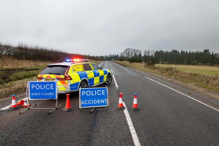 Police car and road closure sign after car crash on B9077 South Deeside Road near Maryculter, Aberdeenshire.