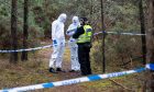Detectives and forensic teams at Oakenhead Wood in Lossiemouth behind police tape.