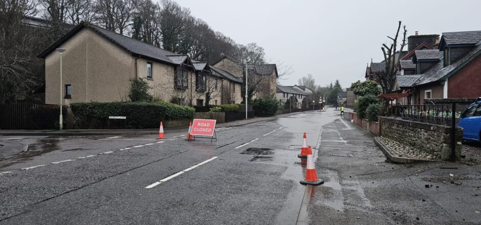 A red road closure sign blocks Direbught Road. 