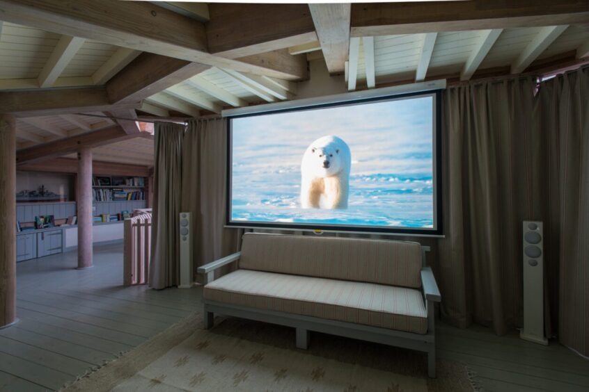 Lounge area with large projector screen in the Mull property featured in Paradise Homes.