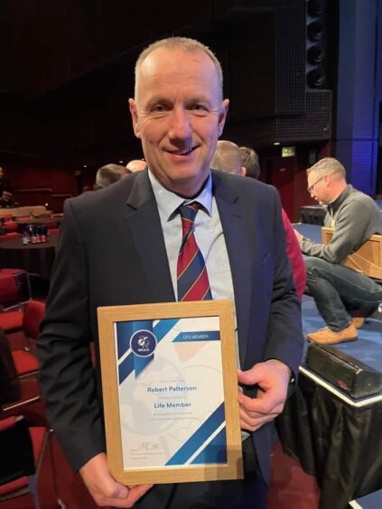 Royal Aberdeen course manager Robert Patterson holding a framed certificate from BIGGA