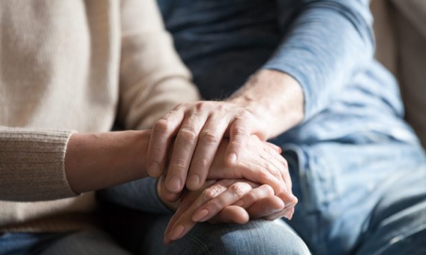 A woman holding the hand of an elderly person, offering support.