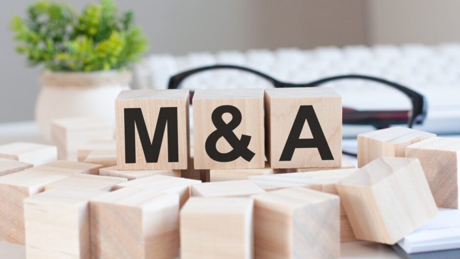 Businesswoman's hand holding wooden blocks spelling out M & A.