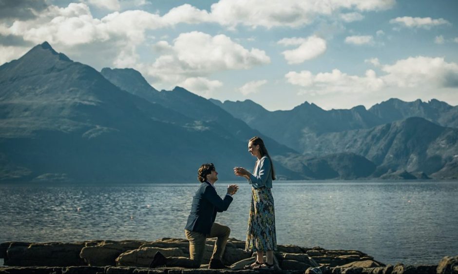 Marriage proposal on Isle of Skye with scenic background.