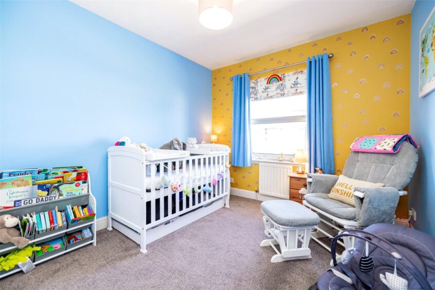 Sky blue nursery with yellow accent wall.