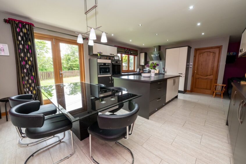 Spacious kitchen in Aldwyn Park House in Auchnagatt, featuring island and dining table.