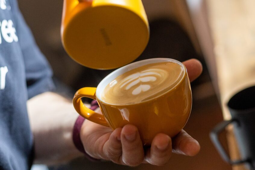 a barista holds a cup of coffee from Fearless Coffee in case you're looking for the best coffee in north-east Scotland