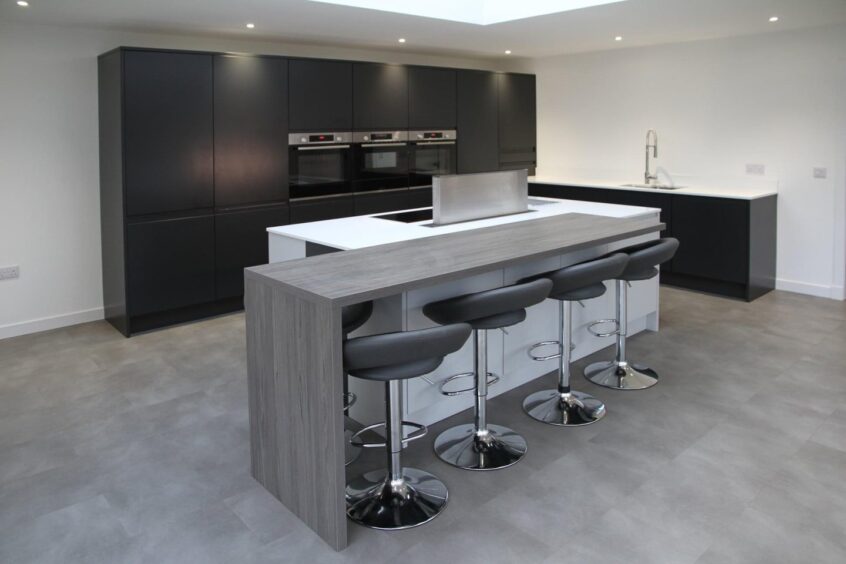 modern kitchen with sleek black cabinets and spacious bar area attached to a huge island