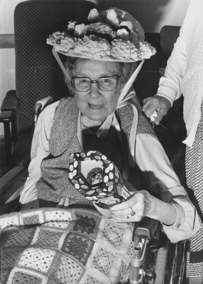 An elderly woman in a wheelchair with an easter bonnet on