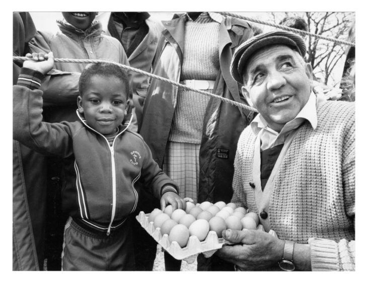 A man with a tray of eggs with a child