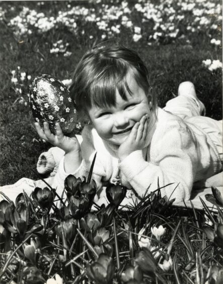 A young girl lying in the grass with an easter egg