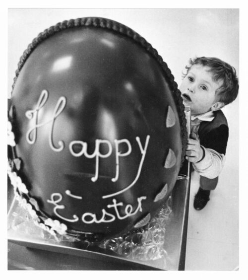 A boy with a giant easter egg with "happy easter" written on it 