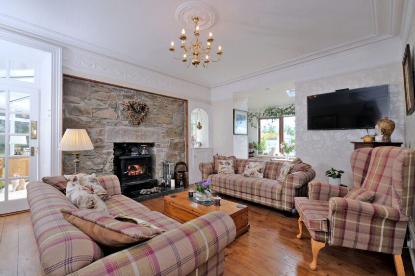The living room with an Exposed stone and a wood-burning stove and cosy plaid sofas and armchairs