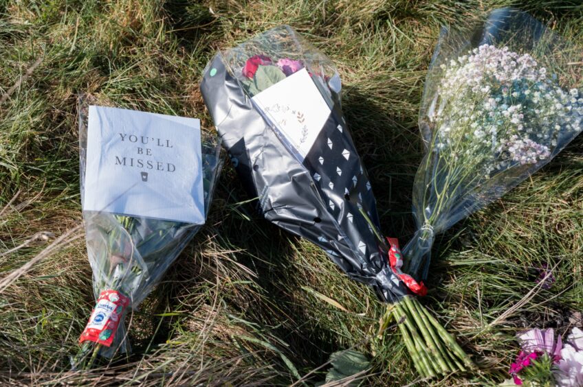 Floral tributes on ground.