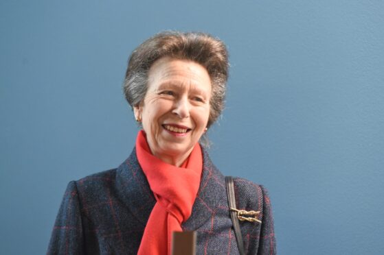 The Princess Royal smiling wearing a red scarf.