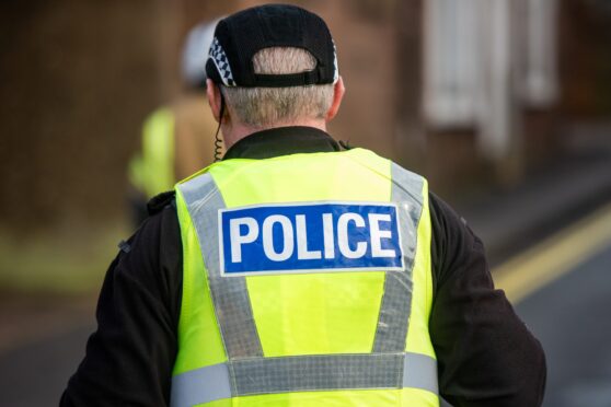 Police officer wearing a black hat and high-vis vest branded with Police on his back.