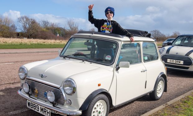 Cameron Parrott, 10, gives a thumbs up as he stands up from within Mini.