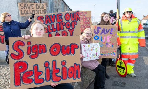 Children hold signs outside Portlethen Primary with lollipop lady Pamela