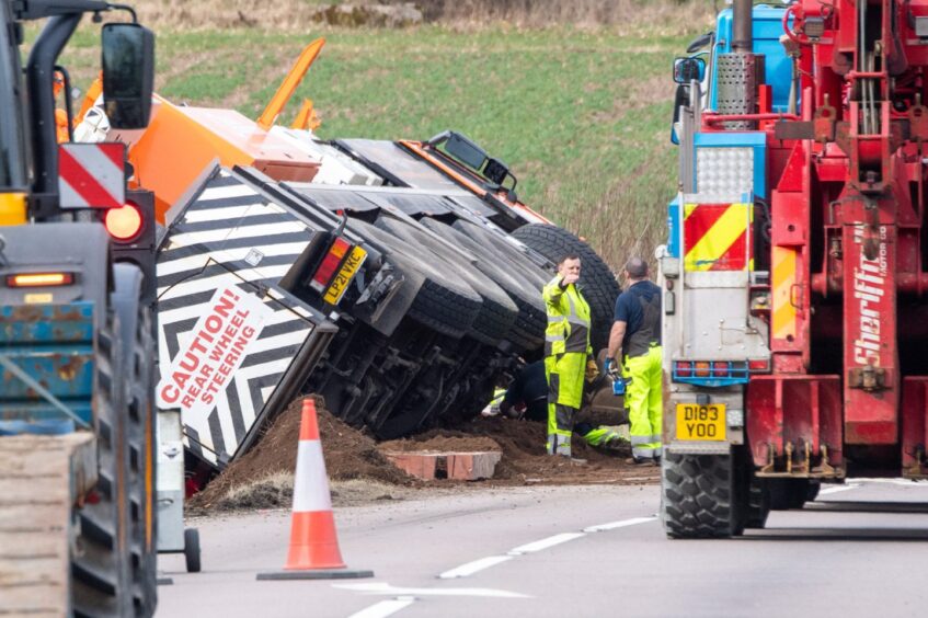 Orange crane lies on its side in a ditch off the A96.