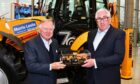 JCB chairman Anthony Bamford, left, presents Morris Leslie with a special scale model version of the Platinum Edition backhoe loader produced to mark the JCB machine’s 70th birthday.