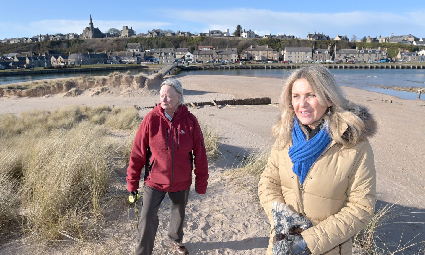 Carolle Ralph and Gina McNicoll on Lossiemouth beach with town behind. 