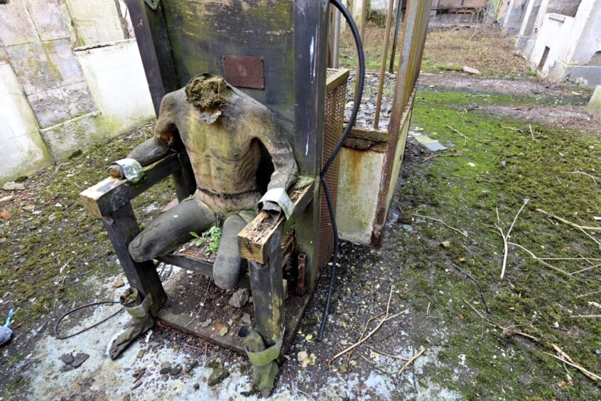A headless dummy sitting on a chair in a courtyard