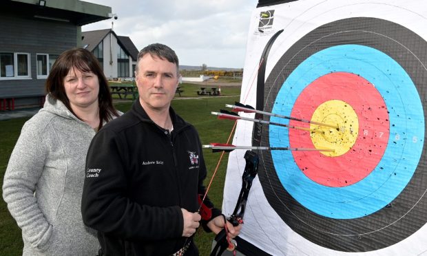 Andrew and Lorraine Kelly next to archery target with arrows.