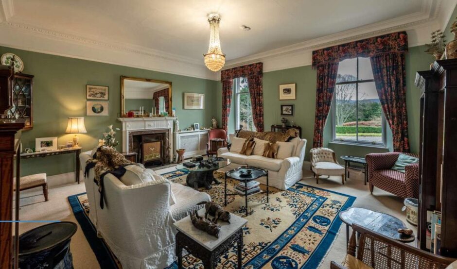 The drawing room with floral curtains, green walls and and white and brown furnishings.. 