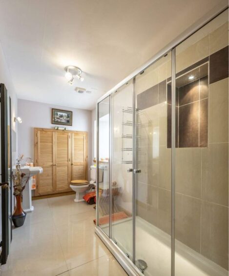 Bathroom with light flooring and a huge walk in shower. 