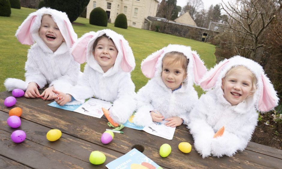 Four children wearing bunny outfits with Easter eggs 