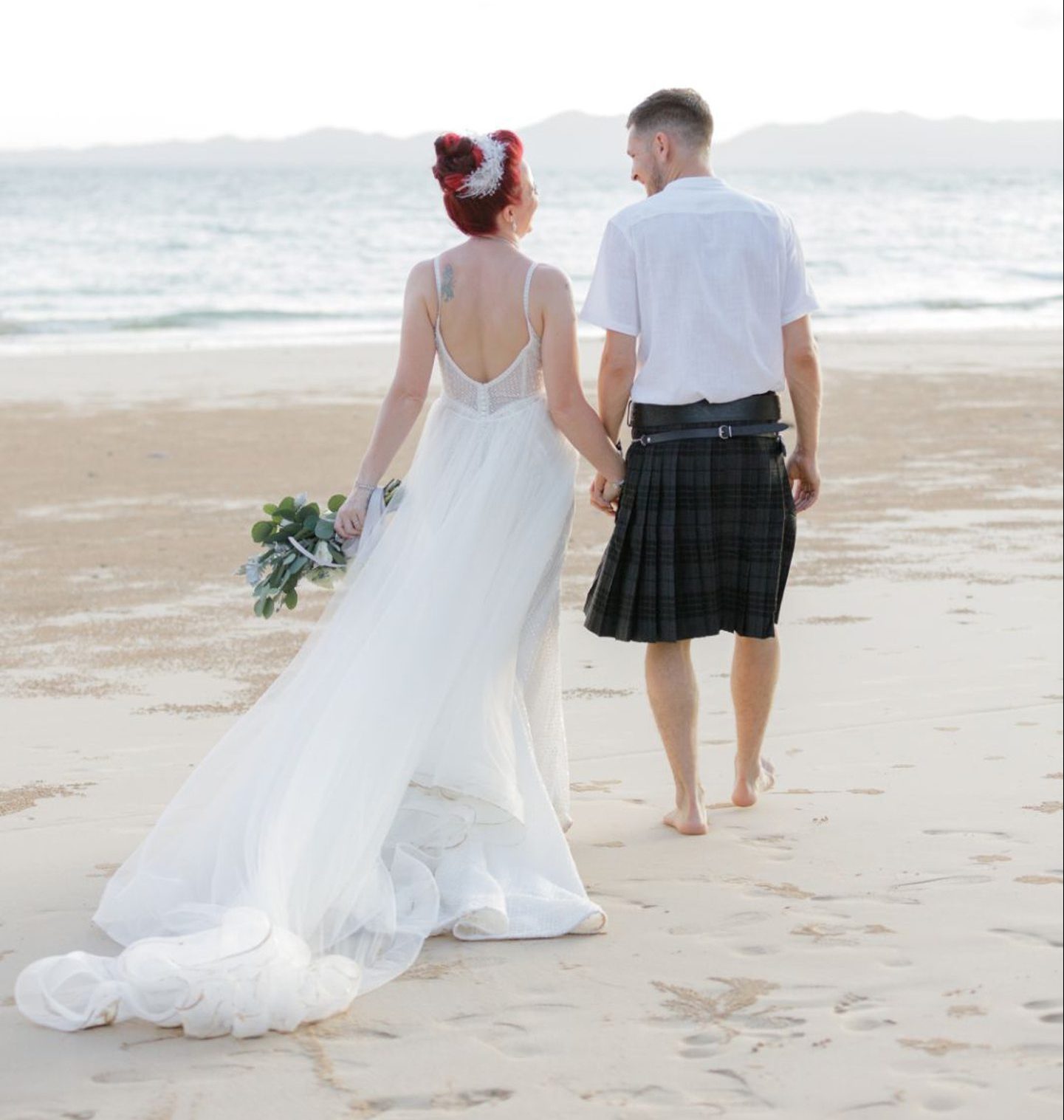 Elaine and Marc Walker on the beach in their wedding dress/kilt on their wedding day in Thailand.