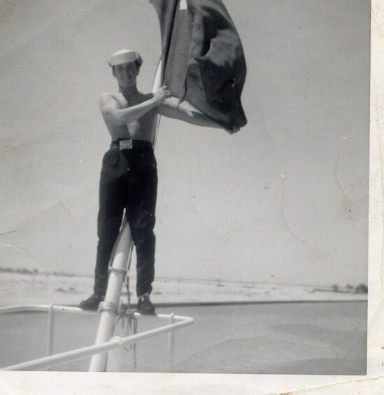 Gordie MacDonald in the Merchant Navy holding a flag. 