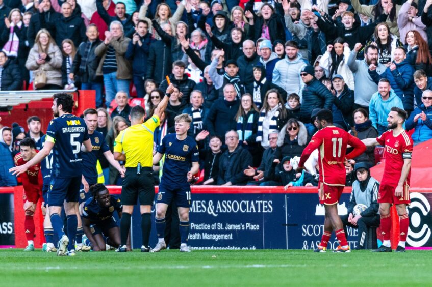 A red card being held up by the referee during the Aberdeen and Dundee game