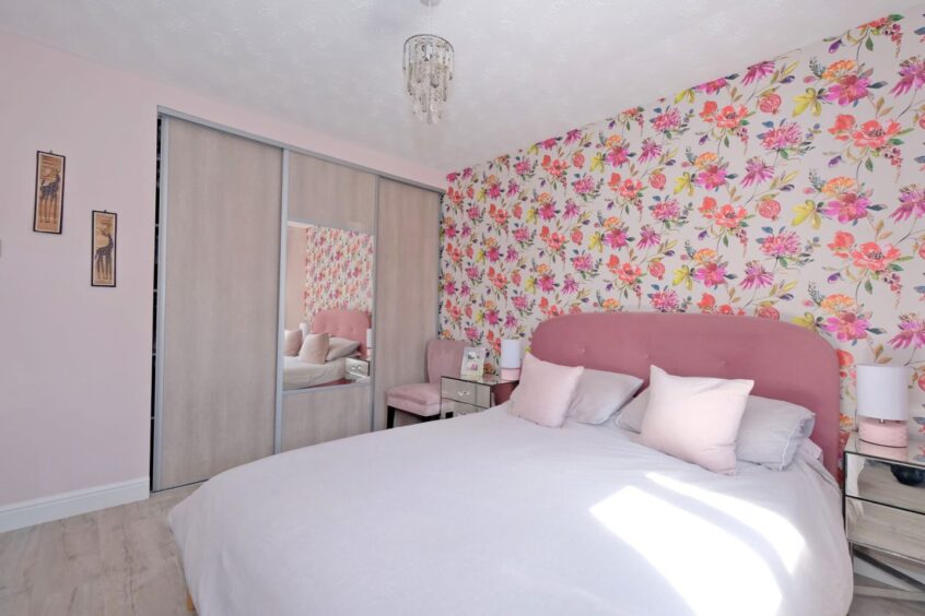 A bedroom in the Newmachar home renovation with a floral accent wall, a built-in wardrobe, a double bed and two mirrored bedside tables