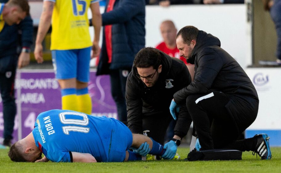 Physios treat a knee injury to Aaron Doran, who is lying on the pitch