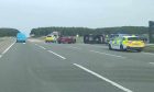 A car on its side surrounded by police cars and other vehicles on the A96.