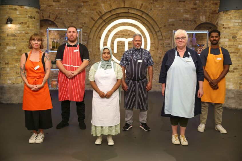 Muir standing alongside her fellow contestants in front of the round M MasterChef sign.