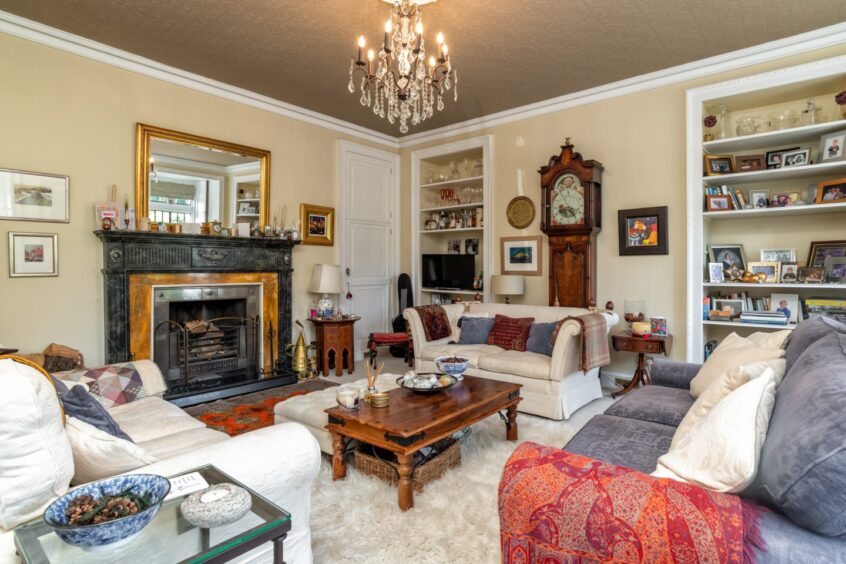 The living room in the home with a grand fireplace, two bookcases and three sofas